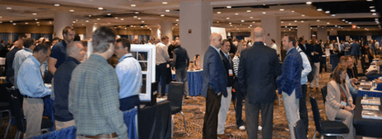 People talk beside exhibit tables at the 2024 LMC Expo