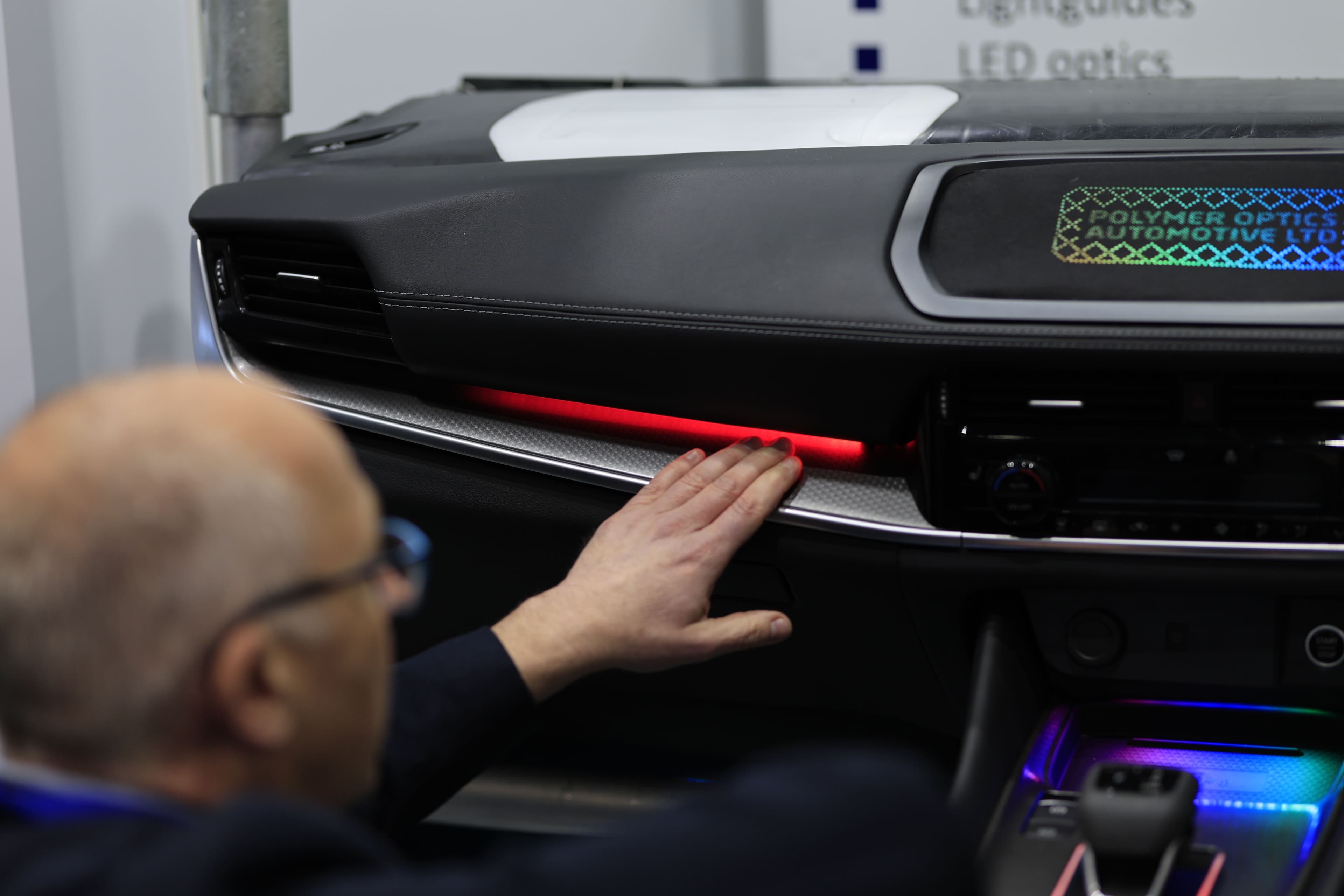 An attendee examines an illuminated dashboard at Automotive Interiors Expo North America