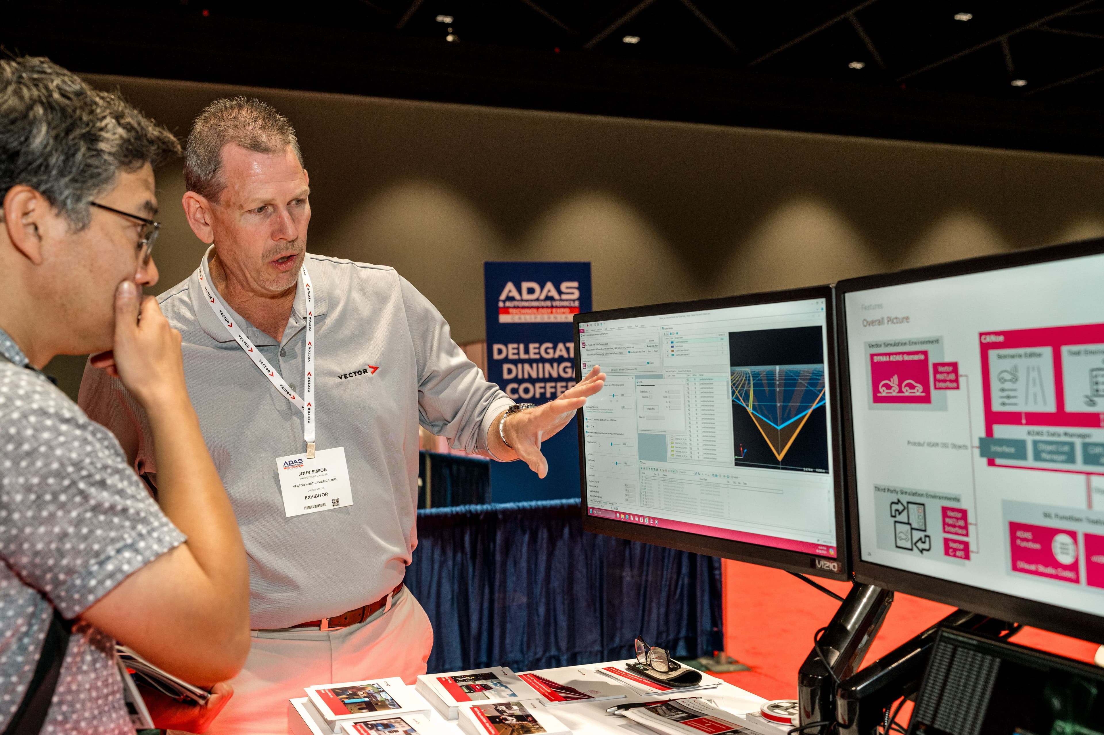Exhibitor demonstrates vehicle simulation software to an attendee