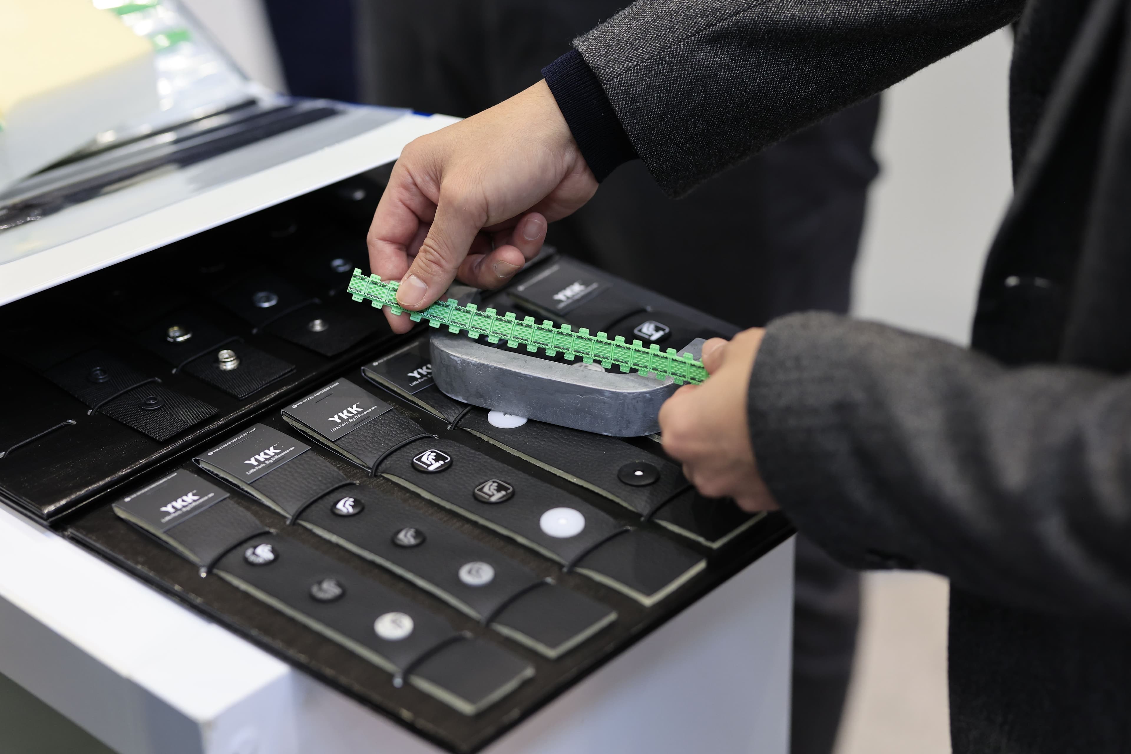 A visitor handles a cabin material sample at Automotive Interiors Expo North America