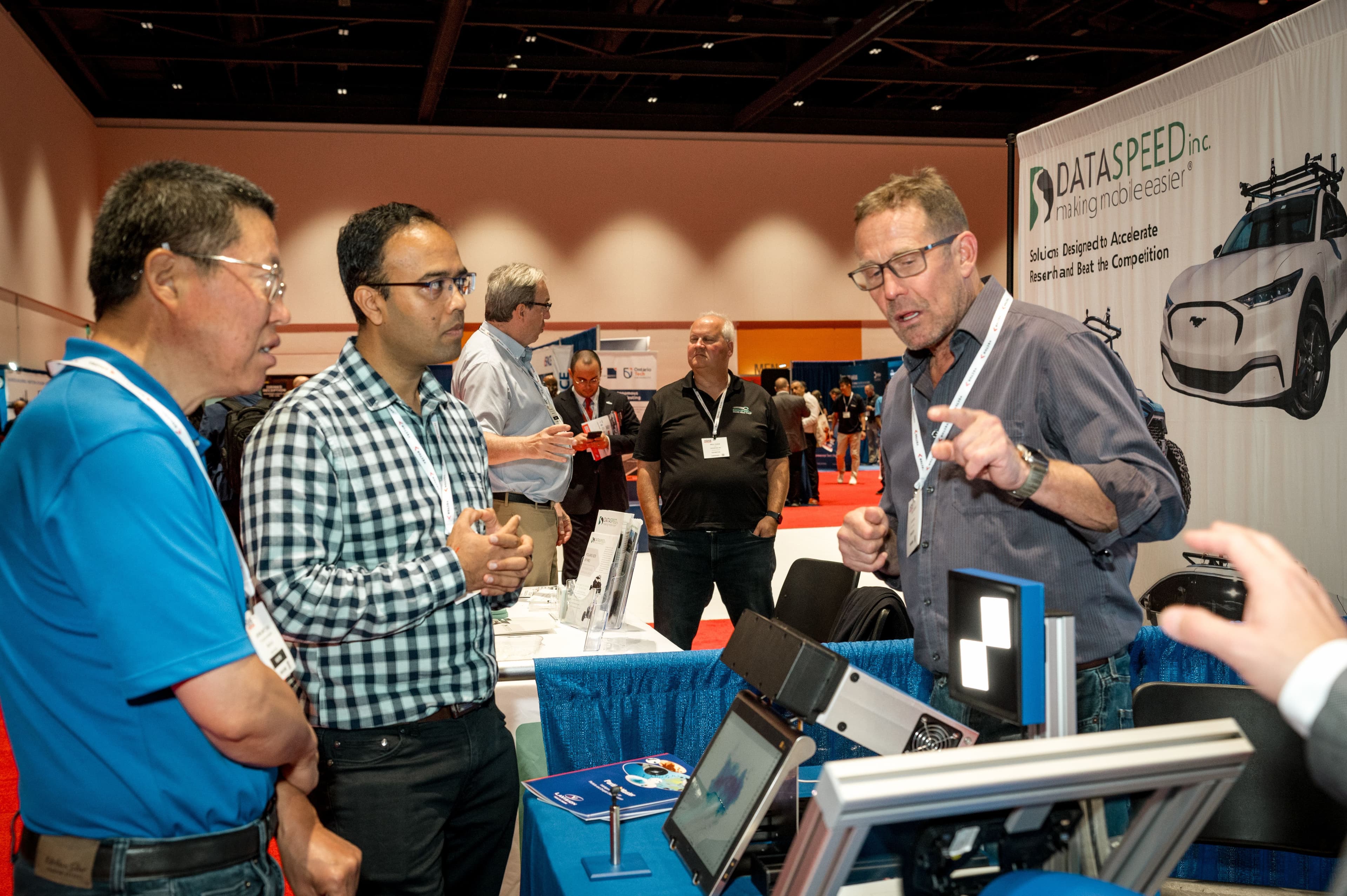 Attendees watch a vehicle technology demonstration at an exhibition stand