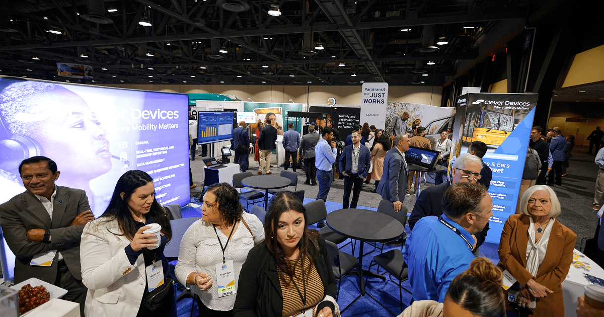 Attendees speaking beside transit technology displays