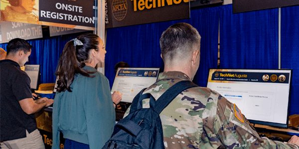 Attendees checking in at TechNet Augusta onsite registration kiosks, including a soldier in Army uniform