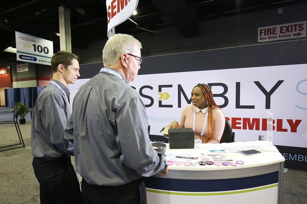 Attendees speaking with event staff on The ASSEMBLY Show floor in 2023