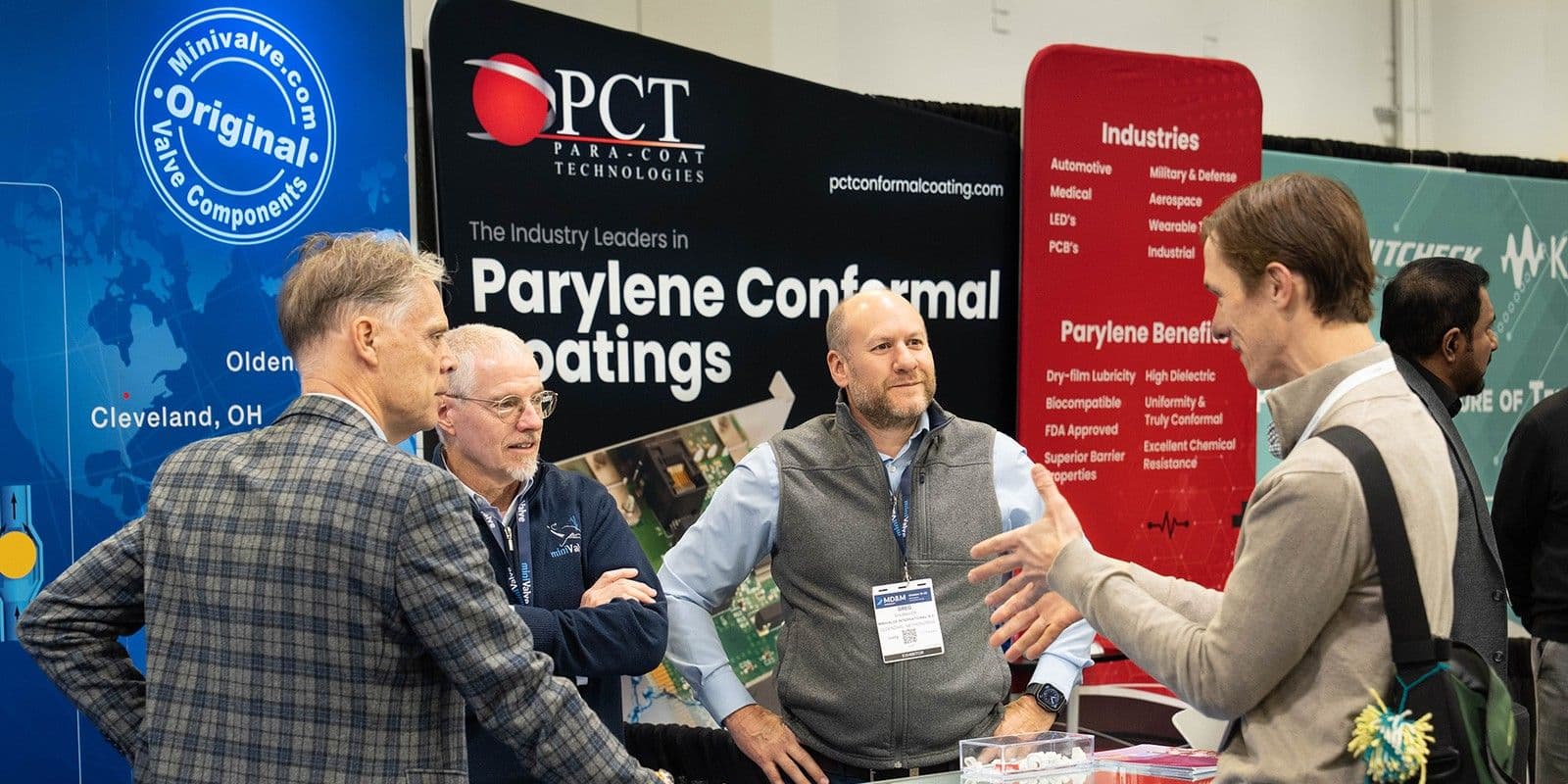 Organizer photograph of visitors talking with medical component exhibitors